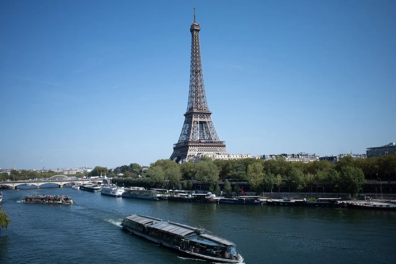 La tour Eiffel et la Seine sous un ciel bleu, un bateau sur le fleuve